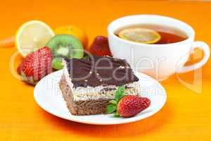 lemon tea, kiwi,cake and strawberries lying on the orange fabric