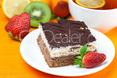 lemon tea, kiwi,cake and strawberries lying on the orange fabric