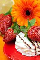 lemon ,gerbera,cake and strawberries lying on the orange fabric