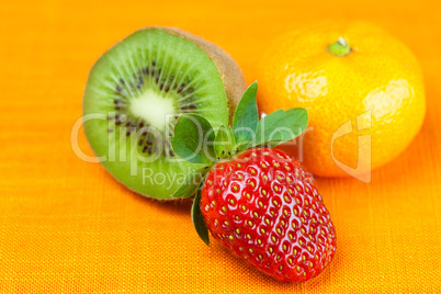 kiwi,mandarin and strawberries lying on the orange fabric