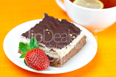 lemon tea, cake and strawberries lying on the orange fabric