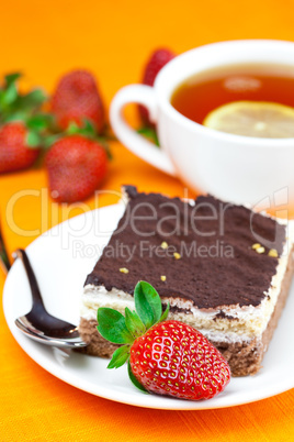 lemon tea, cake and strawberries lying on the orange fabric