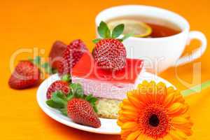 gerbera, lemon tea, cake and strawberries lying on the orange fa