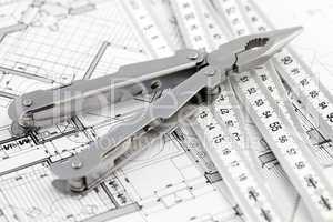 Pliers,  metric folding ruler and architectural plan of the mode