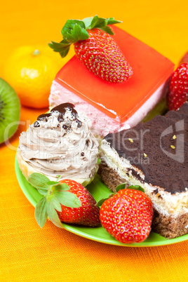 mandarin,kiwi,cake and strawberries lying on the orange fabric