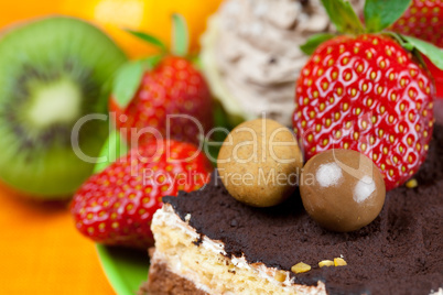 cake, chocolate candy, tangerine, kiwi and strawberries on the o