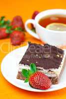 lemon tea, cake and strawberries lying on the orange fabric