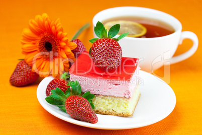 gerbera, lemon tea, cake and strawberries lying on the orange fa