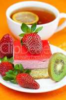 lemon tea, kiwi,cake and strawberries lying on the orange fabric