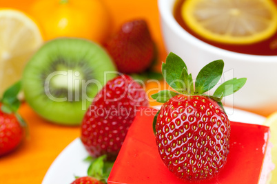 lemon tea, kiwi,cake and strawberries lying on the orange fabric