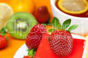 lemon tea, kiwi,cake and strawberries lying on the orange fabric