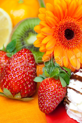 lemon ,gerbera,cake and strawberries lying on the orange fabric