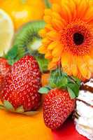 lemon ,gerbera,cake and strawberries lying on the orange fabric