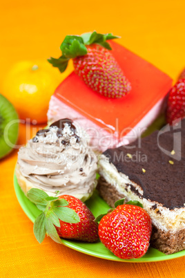 mandarin,kiwi,cake and strawberries lying on the orange fabric