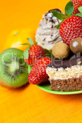 cake, chocolate candy, tangerine, kiwi and strawberries on the o