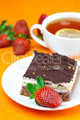 lemon tea, cake and strawberries lying on the orange fabric