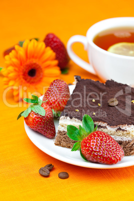 gerbera, lemon tea, cake and strawberries lying on the orange fa