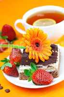 gerbera, lemon tea, cake and strawberries lying on the orange fa