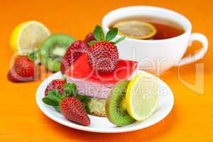 lemon tea, kiwi,cake and strawberries lying on the orange fabric