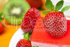 lemon tea, kiwi,cake and strawberries lying on the orange fabric