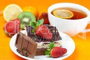 lemon tea,chocolate, kiwi,cake and strawberries lying on the ora