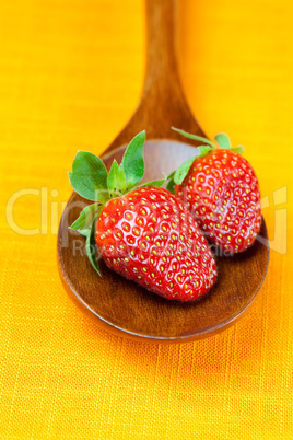 Strawberries in wooden spoon of the orange fabric