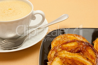 Closeup of coffee with milk in white cup and a palmier pastry