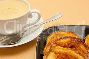 Closeup of coffee with milk in white cup and a palmier pastry