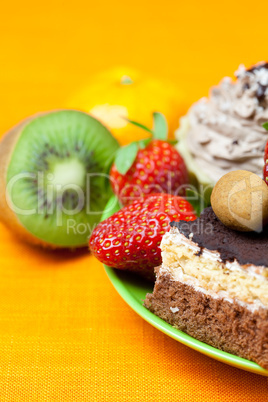 cake, chocolate candy, tangerine, kiwi and strawberries on the o