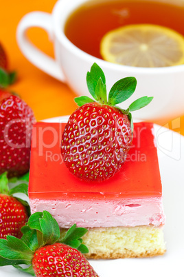 lemon tea, cake and strawberries lying on the orange fabric