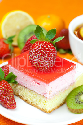 lemon tea, kiwi,cake and strawberries lying on the orange fabric