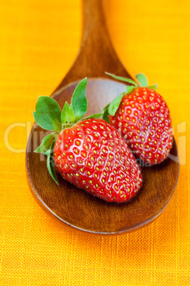 Strawberries in wooden spoon of the orange fabric