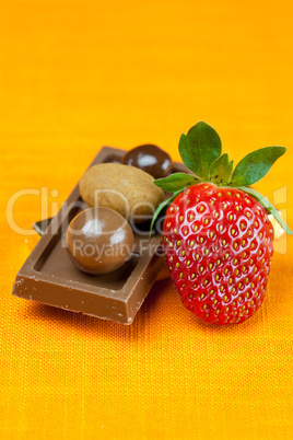 chocolate bars, strawberries and chocolates on the orange fabric