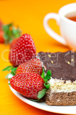 lemon tea, cake and strawberries lying on the orange fabric