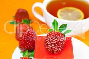 lemon tea, cake and strawberries lying on the orange fabric