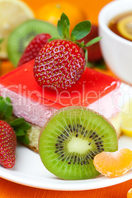 lemon tea, kiwi,cake and strawberries lying on the orange fabric