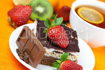 lemon tea,chocolate, kiwi,cake and strawberries lying on the ora