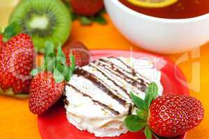 lemon tea, kiwi,cake and strawberries lying on the orange fabric