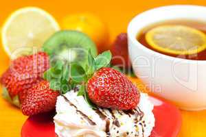 lemon tea,lemon, mandarin, kiwi,cake and strawberries lying on t