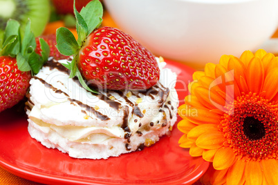 lemon tea,gerbera, kiwi,cake and strawberries lying on the orang