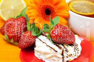 lemon tea ,lemon,gerbera,cake and strawberries lying on the oran