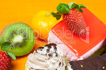 mandarin,kiwi,cake and strawberries lying on the orange fabric