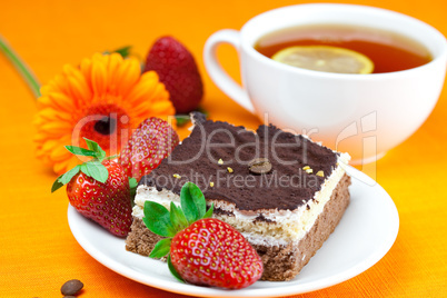 gerbera, lemon tea, cake and strawberries lying on the orange fa