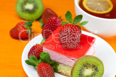 lemon tea, kiwi,cake and strawberries lying on the orange fabric