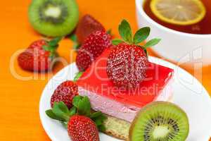 lemon tea, kiwi,cake and strawberries lying on the orange fabric