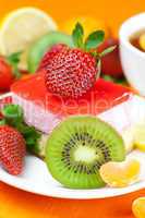 lemon tea, kiwi,cake and strawberries lying on the orange fabric