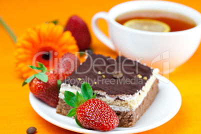 gerbera, lemon tea, cake and strawberries lying on the orange fa