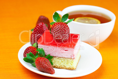 lemon tea, cake and strawberries lying on the orange fabric