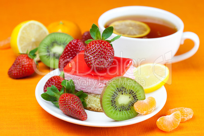 lemon tea, kiwi,cake and strawberries lying on the orange fabric