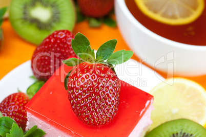 lemon tea, kiwi,cake and strawberries lying on the orange fabric